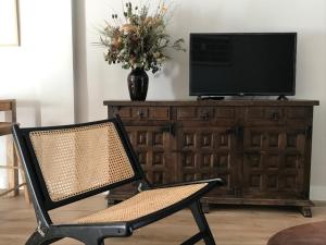a chair in a room with a television on a dresser at Agradable apartamento en el Pantano de San Juan in San Martín de Valdeiglesias