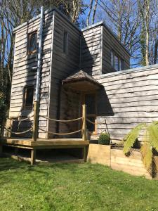 une maison en bois avec une terrasse couverte sur une pelouse dans l'établissement Winnie's Corner - Self Contained within the grounds of another property, in an idyllic wooded setting, à Carlyon Bay