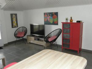 - un salon avec 2 chaises, une télévision et une commode rouge dans l'établissement APPARTEMENT FACE au PORT et à L'OCEAN SAINT GILLES CROIX DE VIE WIFI BALCON PARKING PRIVE COUVERT, à Saint-Gilles-Croix-de-Vie