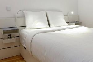 Elle comprend un grand lit blanc avec des draps et des oreillers blancs. dans l'établissement Artury Porto, à Porto