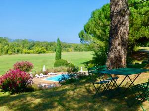 un banco verde junto a un árbol y una piscina en Gîtes Château de la Selve, en Grospierres