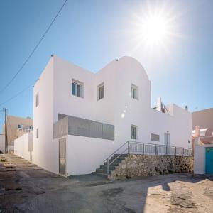 ein weißes Gebäude mit der Sonne im Hintergrund in der Unterkunft Inas House Santorini in Karterados