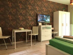 uma sala de estar com uma televisão e uma mesa e cadeiras em Tóparti Wellness Apartman Delux em Velence