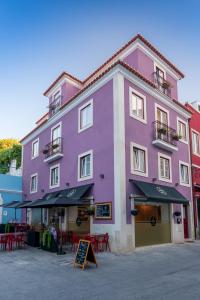 a purple building with tables and chairs in front of it at Vista Lisboa Guest Apartments in Almada