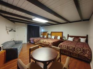 um quarto com duas camas, uma mesa e um sofá em Kootenay Country Inn em Cranbrook