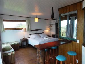 1 dormitorio con cama, mesa y taburetes en Pousada La Luna - Frente Mar, en Barra Velha