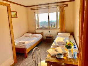 Zimmer mit 2 Betten, einem Tisch und einem Fenster in der Unterkunft Ośrodek Wypoczynkowy u Bartka in Czerwienne