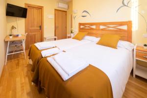 a bedroom with two beds with white sheets and yellow pillows at HOSTAL LA GRANJA ** in Palazuelos de Eresma