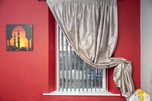 a red room with a window with a curtain at Darlington Town Centre Apartments free parking and Wi-Fi in Darlington