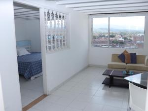 a white living room with a bed and a table at Hotel Don Gregorio in Cartago