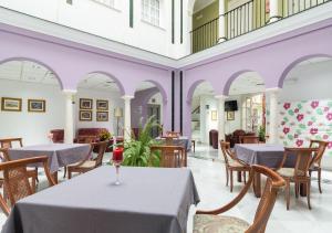 comedor con mesas, sillas y paredes púrpuras en Hotel Platería, en Écija