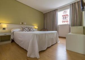 1 dormitorio con cama blanca y ventana en Hotel Platería, en Écija