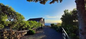 une route menant à un bâtiment avec un mur en pierre dans l'établissement Baía de Canas Villa, à São Roque do Pico