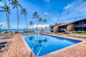 a resort pool with palm trees and the ocean at Mahina Surf in Kahana