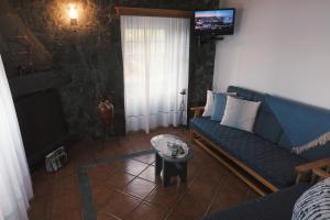 a living room with a blue couch and a tv at Baía de Canas Villa in São Roque do Pico