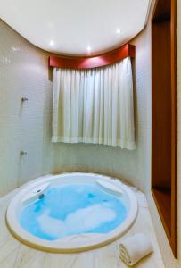 a large blue tub in a bathroom with a window at Suites Hotsprings - Caldas Novas in Caldas Novas