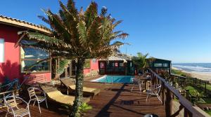 a deck with chairs and a palm tree next to the beach at Pousada La Luna - Frente Mar in Barra Velha