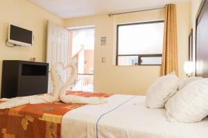 1 dormitorio con 1 cama con 2 cisnes hechos de toallas en Hotel Posada Guadalupe, en Puebla