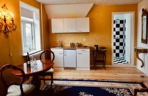 una cocina con armarios blancos y una mesa en una habitación en Old Roses Guesthouse, en Broager