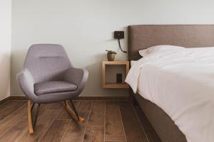 una camera da letto con una sedia accanto a un letto di De Balloo, vakantiehuis met sauna en jacuzzi a Zuienkerke