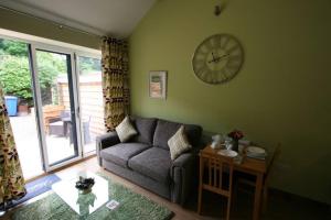 a living room with a couch and a clock on the wall at Larch Cottage, Ruston dog friendly with hot tub in Scarborough