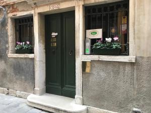 uma porta verde de um edifício com flores nas janelas em Mercerie e Capitello Apartments em Veneza