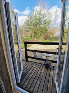 an open door to a deck with a picnic table at Nuthatch Lodge in Kings Lynn +11 photos