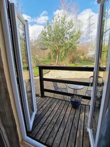 an open door to a deck with a picnic table at Nuthatch Lodge in Kings Lynn