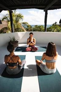 un grupo de personas sentadas en el suelo haciendo yoga en NEST Tulum, en Tulum