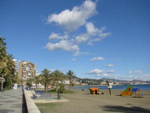 einen Strand mit Palmen und einem Gebäude und dem Wasser in der Unterkunft La Brisa Malagueta in Málaga