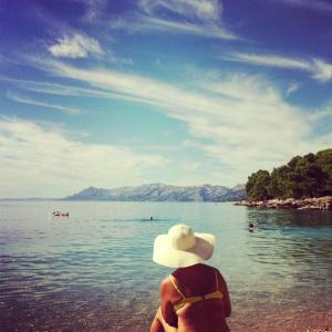 a person sitting on a beach in the water at Apartments Panorama in Makarska