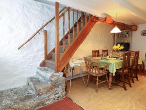 a dining room with a table and a staircase at Mural Cottage in Mousehole