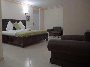 ein Schlafzimmer mit einem Bett, einem Stuhl und einem Sofa in der Unterkunft La Pepiniere Hotel in Pétionville