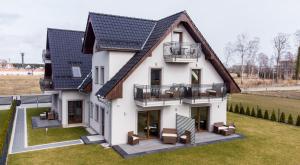 een groot wit huis met een zwart dak bij Aston Vila Apartments in Dziwnów