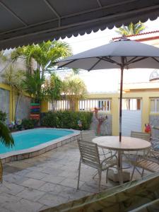 a table with an umbrella next to a pool at Pousada Mananauê Beach in Porto De Galinhas