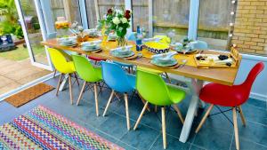 una mesa de madera con sillas de colores y un asterisco en 5 Bedroom House -Sleeps 12- Big Savings On Long Stays! en Canterbury