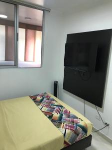 um quarto com uma cama e uma televisão de ecrã plano em Apartamentos Amoblados JG de la 70 em Medellín