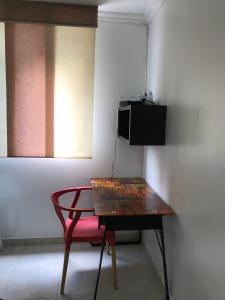 uma mesa com uma cadeira vermelha e uma televisão na parede em Apartamentos Amoblados JG de la 70 em Medellín