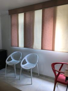 2 sillas blancas sentadas en una habitación con ventanas en Apartamentos Amoblados JG de la 70 en Medellín