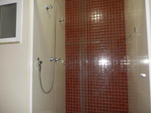 a bathroom with a shower with red tile at Flat entre mar e lagoa II in Arraial do Cabo