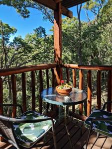 einen Tisch und Stühle auf einer Veranda mit einer Schüssel Blumen in der Unterkunft Shady Creek Eco Cabin, Mudgee, Peaceful Country Getaway in Grattai
