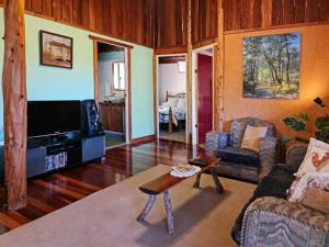 ein Wohnzimmer mit einem Sofa und einem TV in der Unterkunft Shady Creek Eco Cabin, Mudgee, Peaceful Country Getaway in Grattai
