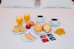 una mesa cubierta con platos de comida y vasos de zumo de naranja en Plaza Motel en Sorocaba