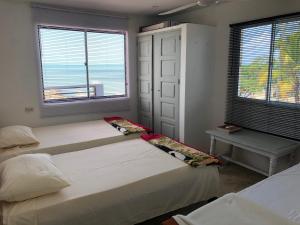 two beds in a room with two windows at "Casa Viña Del Mar" Playa Blanca in San Antero