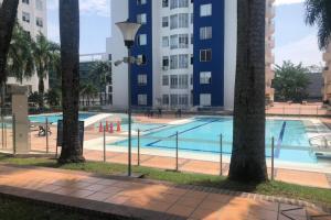 a large swimming pool with palm trees in front of a building at Apartamento, sector exclusivo de Villavicencio in Villavicencio