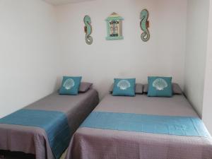 two beds in a room with blue and pink at Posada Smith Town in San Andrés