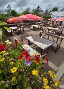 un grupo de mesas de picnic con sombrillas y flores en Auld Cross Keys Inn en Jedburgh