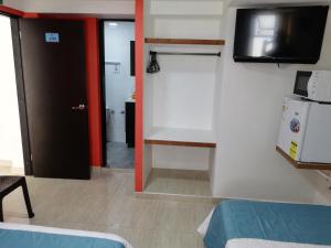 um pequeno quarto com uma televisão e um frigorífico em Posada Smith Town em San Andrés