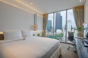 a hotel room with a large bed and a large window at Amara Bangkok Hotel in Bangkok