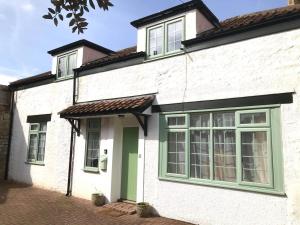 Casa blanca con ventanas verdes y puerta en Hill Cottage en Weston-super-Mare